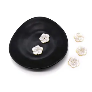 Natural white shell flower pendants for DIY jewelry making displayed on a black plate