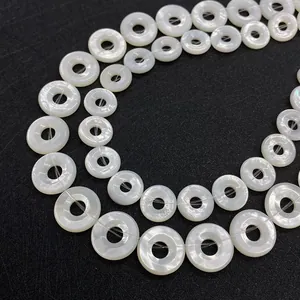 Natural white mother of pearl donut beads arranged in circular patterns on black background