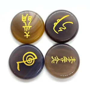 Detalle de cuatro piedras Reiki pulidas con símbolos sagrados grabados en color oro