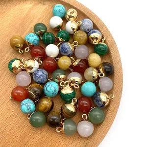 Assorted natural stone round pendants with gold loops on a minimalist wood tray