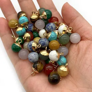 Natural round stone pendants with gold caps held in hand for DIY jewelry making