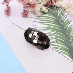 Detailed view of oval mosaic abalone shell bead with iridescent checkerboard pattern