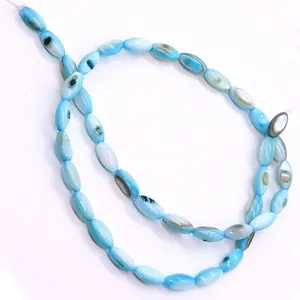 Detailweergave van lichtblauwe rijstvormige schelpkralen met natuurlijke glans voor DIY-sieraden