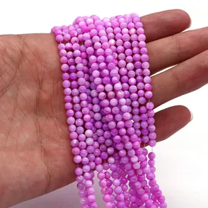 Vista ravvicinata di fili di perle in conchiglia naturale rosa viola in mano