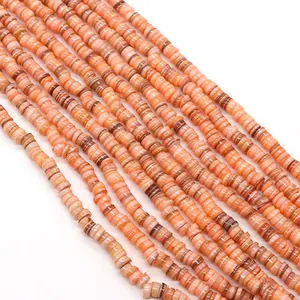 Dettaglio macro di perle heishi in conchiglia naturale arancione per gioielli fai da te