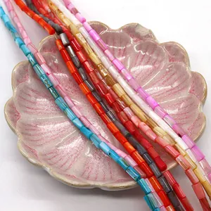 Perline a tubo in conchiglia naturale colorata esposte su un vassoio di ceramica rosa