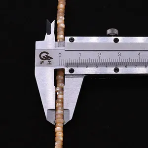 Primer plano de cuentas de concha naranja de 4mm medidas con un calibre de precisión
