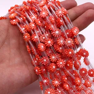 Detailed view of hand-held orange and white daisy shell beads for DIY jewelry making