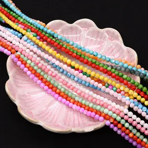 Perline tonde in conchiglia naturale colorata su piatto rosa per creazione gioielli DIY