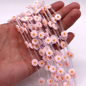 Detail showing hand-held bundle of pink daisy natural shell flower charms for DIY jewelry
