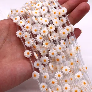 Close-up of white daisy flower beads held by hand for DIY necklace accessory