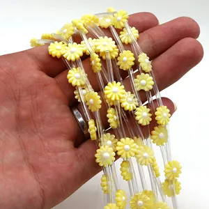 Close-up of yellow daisy shell beads and transparent tubes for DIY jewelry making