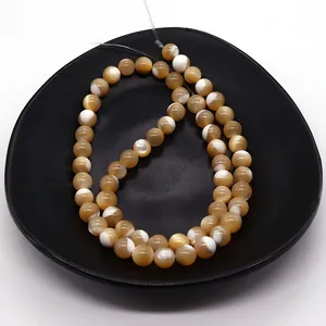 Detailed view of natural shell round beads with brown textures in a black tray for DIY jewelry