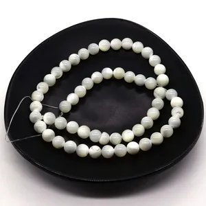 Macro shot of natural white shell beads with iridescent luster on a black matte tray