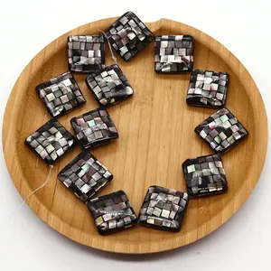 Detailed view of square mosaic shell beads with iridescent inlay on a wooden tray
