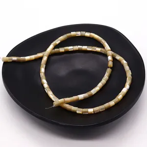 Natural cylindrical shell beads for DIY jewelry making displayed on a black matte tray