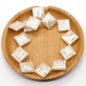 Macro detail of square mother of pearl mosaic beads in a rustic wooden tray
