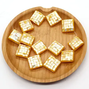 Macro detail of square yellow shell mosaic beads on wood tray for DIY jewelry
