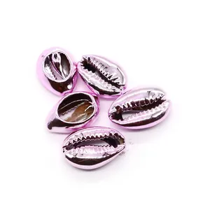 Close-up of five bright pink electroplated natural cowrie shells for DIY jewelry making