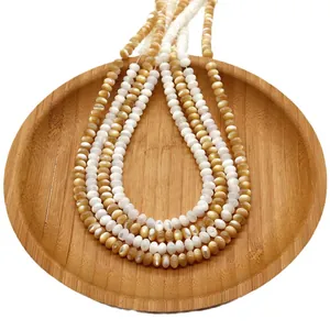 Natural sea shell beads for DIY necklaces shown in a wooden tray on white background