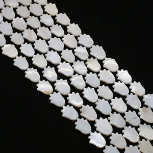 Macro shot of white mother of pearl shell beads in hamsa hand shape for jewelry making