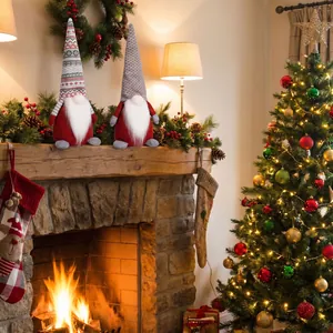 Detail of two Christmas gnomes with knitted hats sitting on a festive stone fireplace