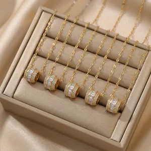Five gold titanium necklaces with zircon pendants displayed on beige velvet
