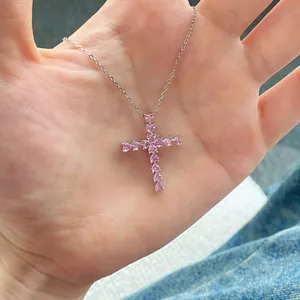 Collier croix en argent S925 serti de zircons roses en forme de cœur tenu à la main