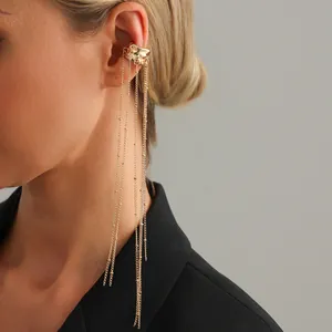 Elegant macro close-up of a gold-colored ear cuff with long dangling tassel chains.
