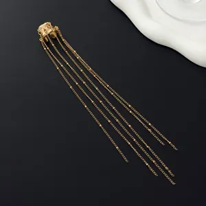 Detailed close-up of a gold ear cuff featuring long multi-strand beaded tassel chains