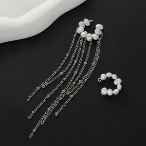 Close-up of silver-tone ear cuffs featuring Baroque pearls and long chain tassels.