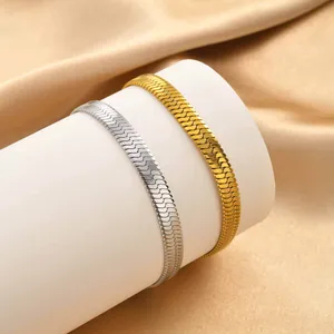 Detail view of gold and silver flat snake bone chain bracelets on a soft satin fabric