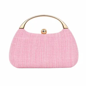 Macro detail of pink woven texture and light gold metal handle on evening clutch bag