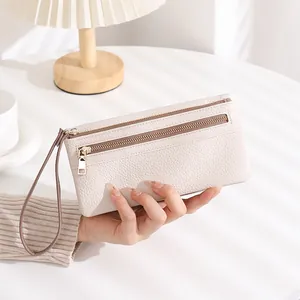 Detail view of beige lychee texture leather wallet with double zipper and wristlet strap