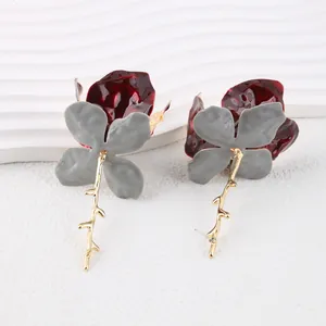 Artistic heavy metal flower earrings with red enamel petals and gold branch pendants