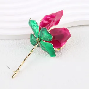 Close-up of vibrant enamel rose flower earrings with green leaves and gold stem