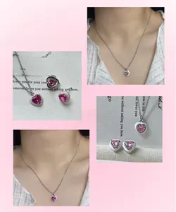 Macro detail of silver heart necklace and earrings with pink zircon on soft pink background