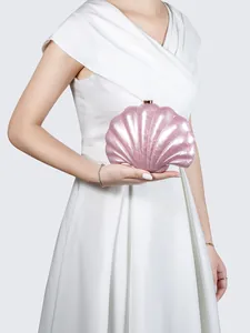 Detailed close-up of pearlescent pink shell-shaped acrylic clutch with gold metal clasp