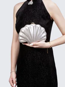 Detail of shell-shaped acrylic evening clutch with pearlescent finish and gold clasp