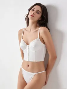 Détail du haut corset en satin blanc avec bordure en dentelle et fermeture frontale