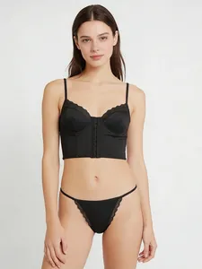 Détail d'un ensemble lingerie en satin noir avec agrafe avant et dentelle fine