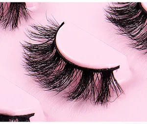Detailaufnahme dicker, geschwungener schwarzer künstlicher Wimpern auf rosa Schale