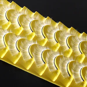 Tien paar witte synthetische valse wimpers voor feestelijke make-up op een geel bakje