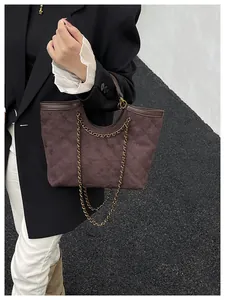 Macro detail of dark brown suede tote bag featuring quilted diamond pattern and gold chain