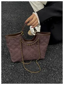 Close-up of quilted dark brown suede tote bag featuring gold chain and leather trim detail