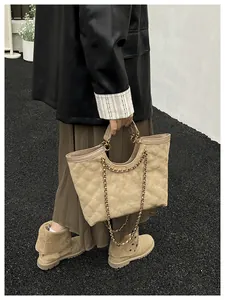 Detail of beige quilted tote bag with gold chain strap and suede texture in street style