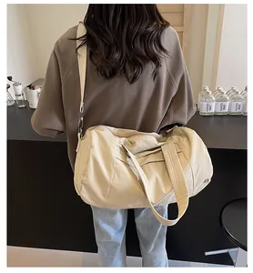 Vista dettagliata di una grande borsa da viaggio in nylon beige indossata a tracolla in un caffè