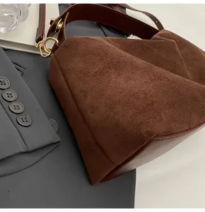 Détail du sac Boston en daim marron avec boucles dorées et large bandoulière chic