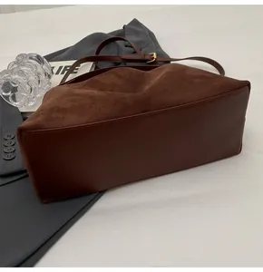 Détail d'un sac Boston en daim marron foncé et cuir lisse avec boucle en métal doré