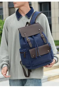 Detail of vintage canvas backpack featuring drawstring closure and leather flap straps